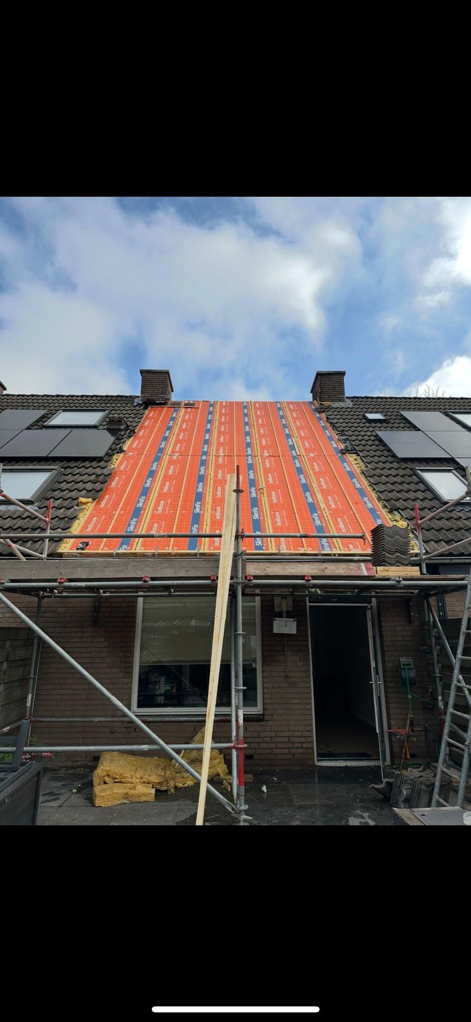 Dakrenovatie met zonnepanelen en steigerconstructie.